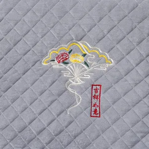 Macro detail of refined fan and floral embroidery on grey quilted fabric chair pad