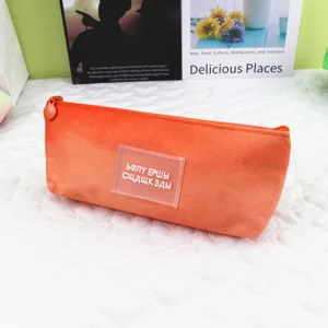 Close-up of orange textured pencil case with central patch on a white quilted mat