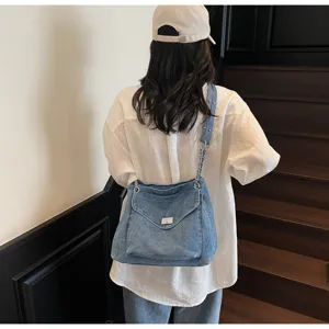Sac cabas en denim lavé élégant avec bandoulière en chaîne porté à l'épaule