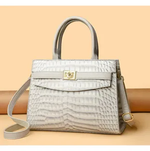 Detailed view of a grey crocodile-embossed tote bag featuring a golden floral lock