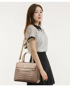 Elegant beige crocodile embossed leather handbag with gold lock worn by an Asian model