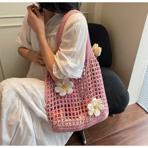 Vista detallada de un bolso de malla rosa con flores blancas decorativas llevado por modelo