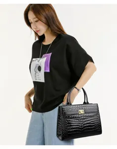 Elegant black crocodile pattern handbag with gold rose lock shown with model in casual style.