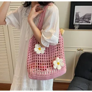 Primer plano de un bolso tote de malla de ganchillo rosa con flores blancas y estilo