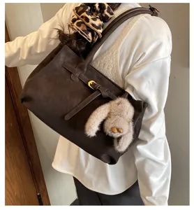 Detailed view of brown matte suede shoulder bag with decorative belt and bunny charm