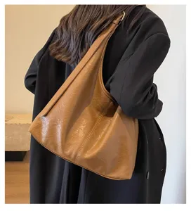 Detailed shot of a vintage brown leather hobo bag worn by a model in a black blazer.