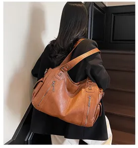 Detail view of a large brown faux leather tote bag worn by a stylish model on stairs