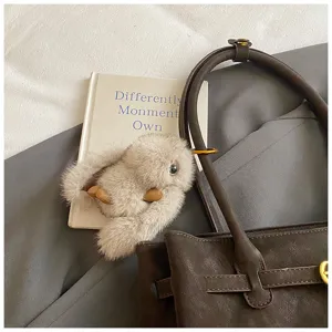 Detail view of a brown frosted suede tote bag featuring a cute plush animal charm.