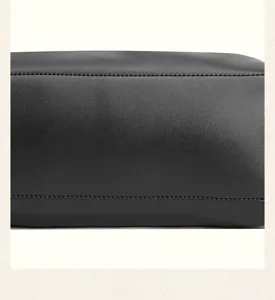 Close-up detail of black leather bag showing fine stitching and smooth texture