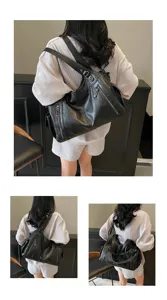 Rear and side views of a large black leather tote bag being carried by a model indoors