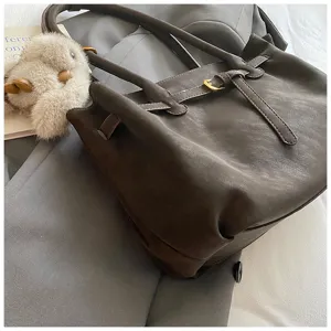 Macro view detail of retro brown suede tote bag with decorative belt and gold buckle