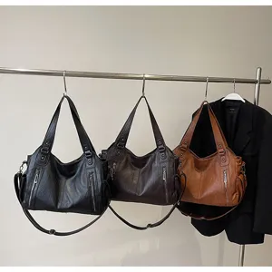 Detailed view of large capacity tote bags in black, brown, and tan colors on a rack