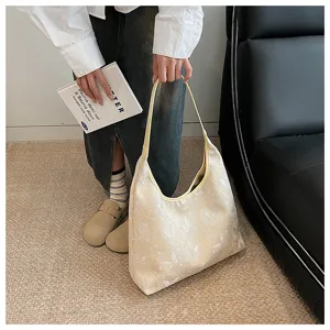 Détail du motif de papillon brodé sur un sac fourre-tout beige au design minimaliste