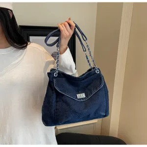 Détail du sac cabas en jean délavé avec bandoulière chaîne argentée et fermoir en métal