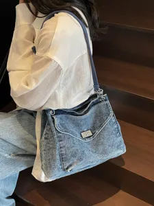 Sac à bandoulière en denim lavé vintage avec fermoir en métal sur un escalier en bois