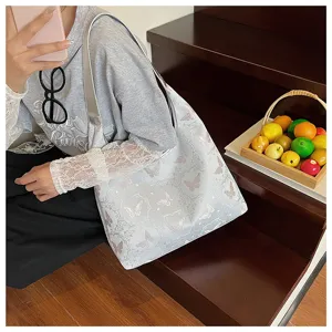 Vue détaillée de l'élégante broderie papillon sur ce grand sac cabas argenté de luxe