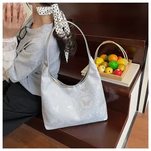 Gros plan du motif de papillon brodé sur un grand sac cabas bleu clair pour femme.