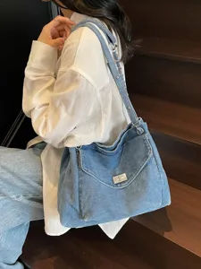 Sac fourre-tout en denim délavé avec fermoir argenté et bandoulière chaîne pour femme.