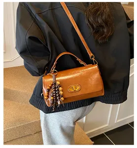 Stylish retro brown leather crossbody bag with unique wooden bead charm detail for women.