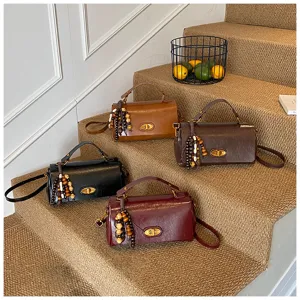 Retro style small square handbags in black brown and burgundy colors on carpeted stairs