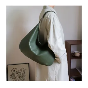 Close-up of a green retro soft leather tote bag worn as a stylish underarm shoulder bag