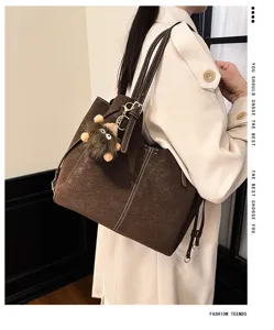 Large brown suede-textured tote bag with monster keychain shown on model shoulder