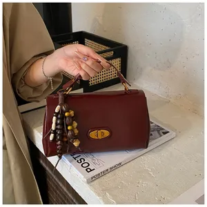 Close-up of a vintage burgundy leather square handbag with beaded tassel detail.