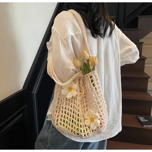 Bolso de malla hecho a mano con ganchillo y flores blancas tejidas usado por modelo en la escalera