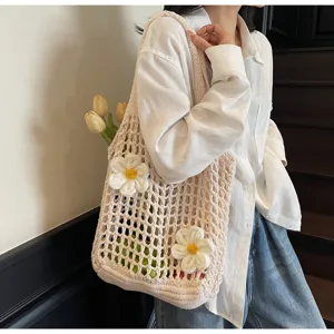 Primer plano de un bolso tote de ganchillo beige con flores blancas llevado al hombro