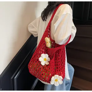 Bolso de malla de ganchillo rojo con flores blancas, visto en una toma de hombro real
