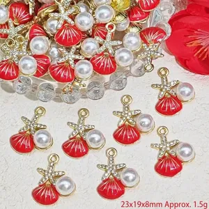 Macro view of red enamel shell jewelry charms featuring faux pearl and gold starfish accents.