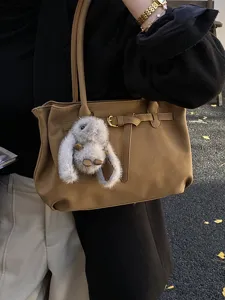 Detail view of a vintage matte suede tote bag with decorative buckle and plush bunny charm