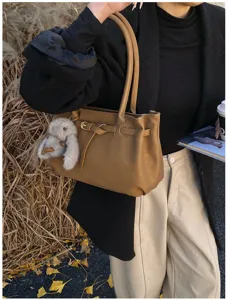 Elegant vintage camel shoulder tote bag featuring decorative belt and plush rabbit charm
