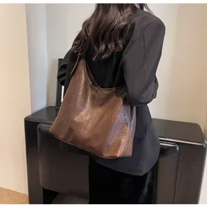 Back view of a vintage brown leather hobo tote bag on a model wearing a black blazer.