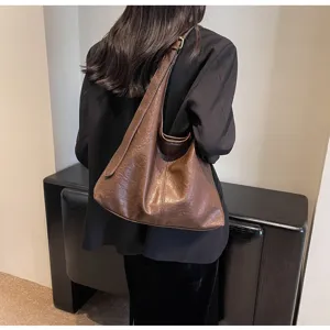 Detailed back view of a vintage brown leather hobo bag worn by a model in a black blazer.