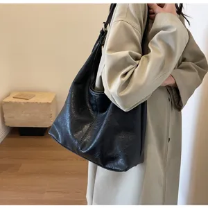 Large vintage black textured hobo bag worn by model in a beige coat