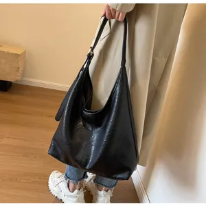 Large black retro leather hobo tote bag worn as a stylish underarm shoulder bag lifestyle view.