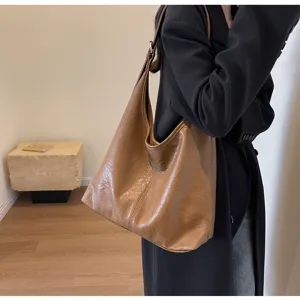 Close-up of a stylish vintage brown leather tote bag carried on a woman's shoulder.