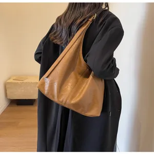 Rear view of model wearing a black coat carrying a brown vintage leather tote bag