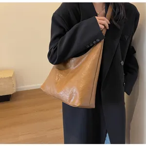 Retro brown textured leather tote bag worn as a stylish and functional underarm shoulder bag