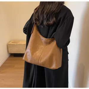 Fashionable brown textured faux leather hobo bag worn by a model in a black coat