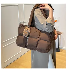Detail view of the brown quilted puffer tote bag with cute plush bear pendant for daily commuting.
