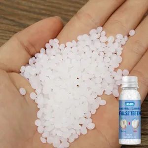Gros plan de granulés thermofomables blancs pour la réparation des dents dans la main.