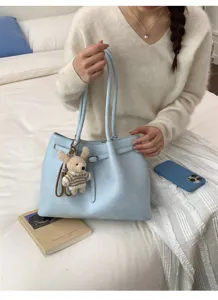 Détail d'un sac cabas en cuir souple bleu clair orné d'un joli pendentif en forme d'ours
