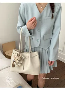 Détail d'un sac cabas en cuir plissé crème avec un joli charme de petit ours en peluche