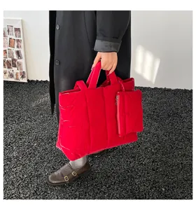 Detailweergave van een grote rode gewatteerde draagtas met bijpassend zakje voor damesmode.