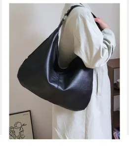 Large black oil wax leather hobo bag worn by model, minimalist retro commuter style