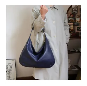 Detailed shot of large navy blue oil wax leather hobo bag held by a model