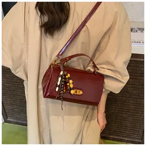 Close-up of a retro burgundy leather handbag worn by a model in a beige coat