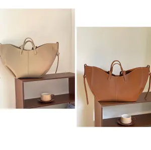 Two large capacity minimalist leather tote bags in beige and brown on a wooden shelf display